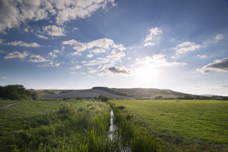 Small,stream,flowing,through,countryside,landscape,on,summer,day